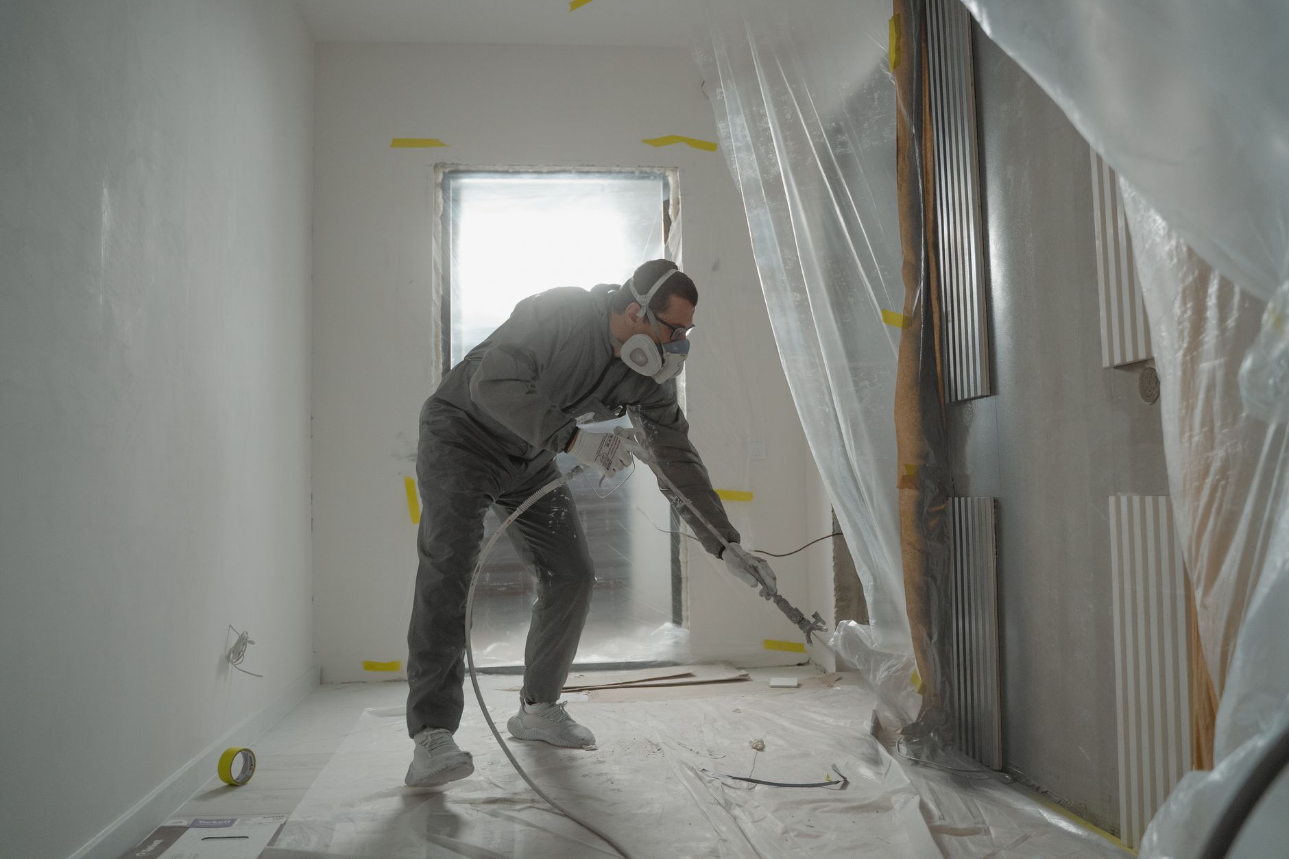 A worker in protective gear painting walls during an indoor renovation project in Rancho Cucamonga, CA