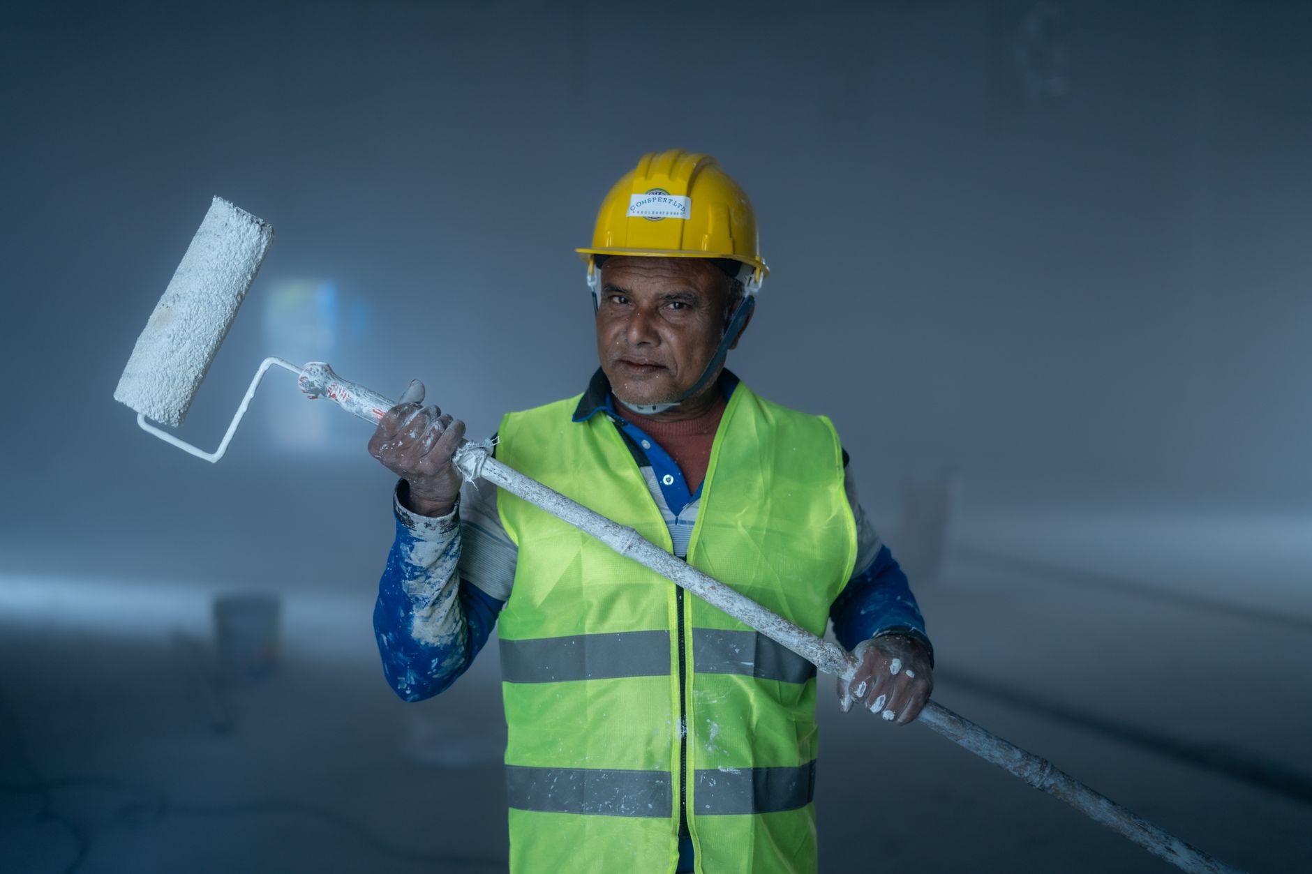 An adult male painter holding a paint roller during a construction project indoors in Rancho Cucamonga, CA